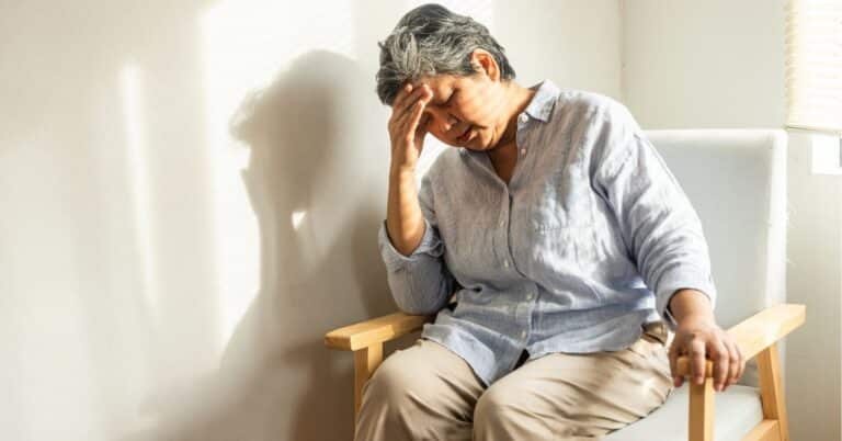 senior-woman-in-dementia-care-holding-her-forehead