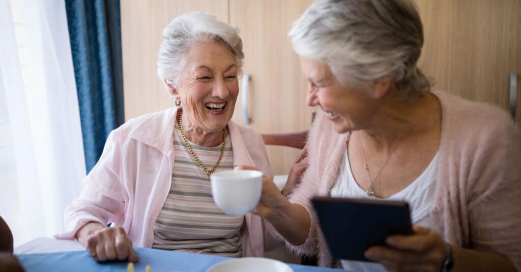 How To Make Assisted Living Feel Like Home For Your Loved One 1 Two-Senior-Women-Friends-Drinking-Coffee-Together-And-Laughing